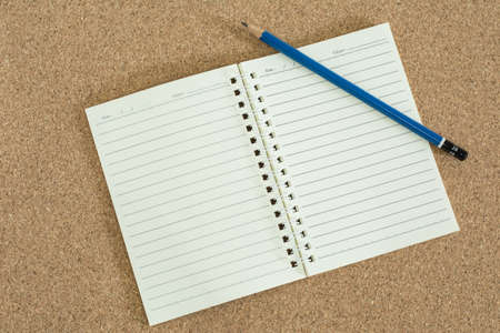 Blank notebook with pencil on cork board background.の写真素材