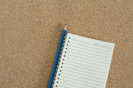 Blank notebook with pencil on cork board background.の写真素材