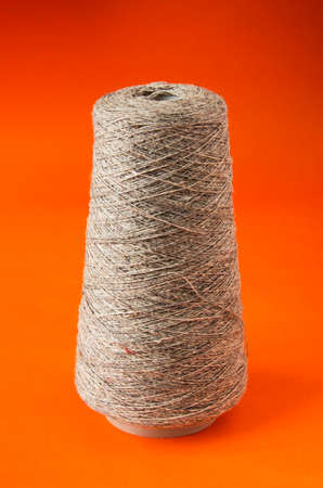 a large spool of beige harsh threads on an orange backgroundの写真素材