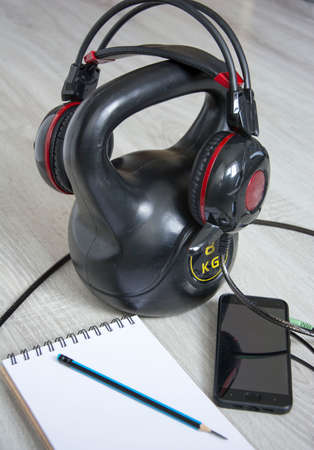 Gymnastic kettlebell with music headphones and a notebook for recording results for active sports at home. Home training concept, healthy lifestyleの写真素材