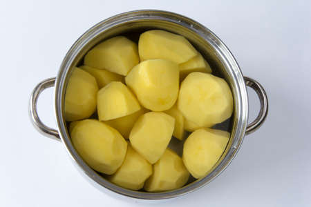 Peeled sliced potatoes lie in water in a saucepan ready to cook on the stoveの写真素材