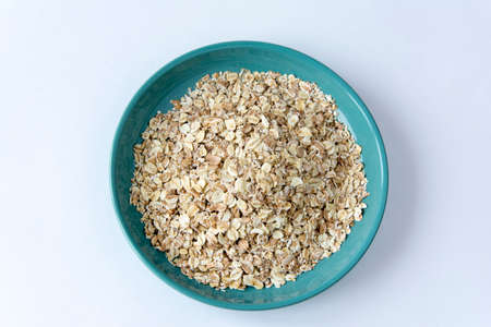 oatmeal flakes in a turquoise plate on a white background, healthy breakfast, herculesの写真素材