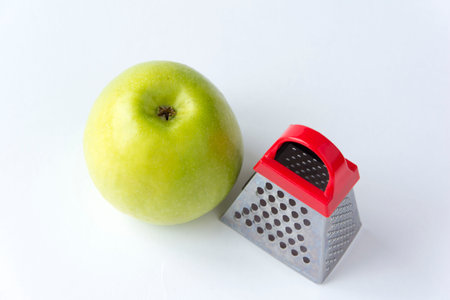 Juicy ripe green apple and a small grater, isolated on a white backgroundの写真素材
