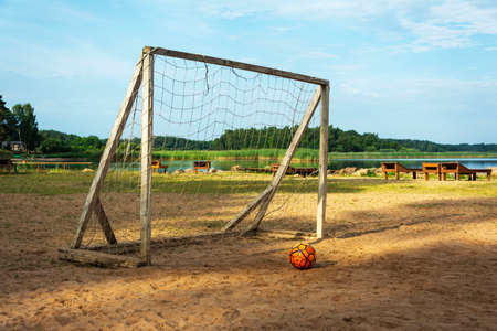 Soccer goal and ball on the beach. Sunlight, water and sand. The beach on the lake of the tourist base. Summer vacation.の写真素材
