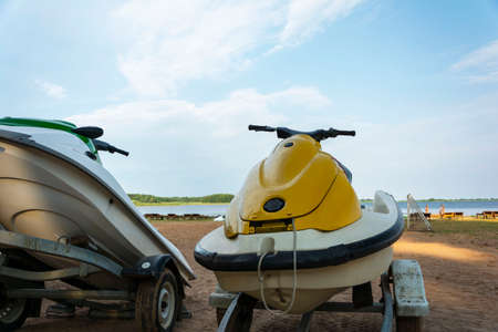 A jet ski parked on the beach against the background of the lake and the blue sky. For the design of an active lifestyle.の写真素材