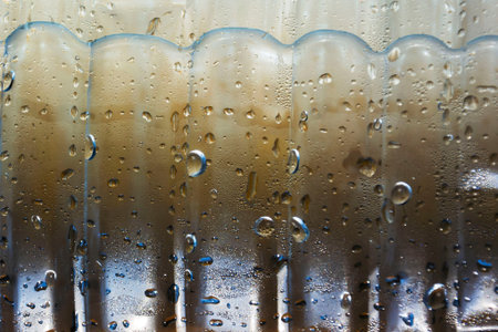 drops of condensate drain from a cold bottle of drinking water on a hot day, abstract background...