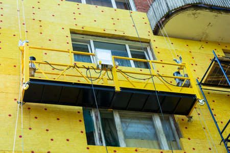 Insulation of the walls of a multi-storey building, construction of a multi-storey building. Thermal insulation of the exterior walls of the house. Thermal insulation materials, mats, plates. The cradle of the lift.の写真素材