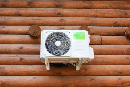 Outdoor air conditioning on the wooden wall of a log private house, climate, cools, heat, comfortable housing.の写真素材