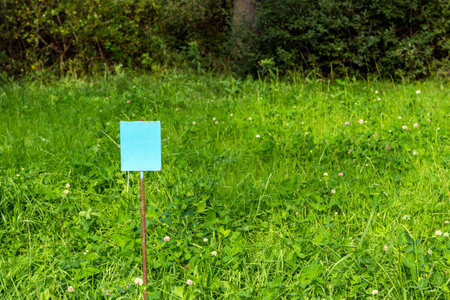 An empty warning sign on a green lawn, a warning sign.