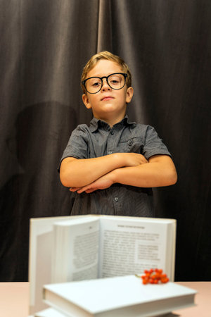 a boy with glasses folded his arms on his chest, a serious look, a stack of books, back to school,...