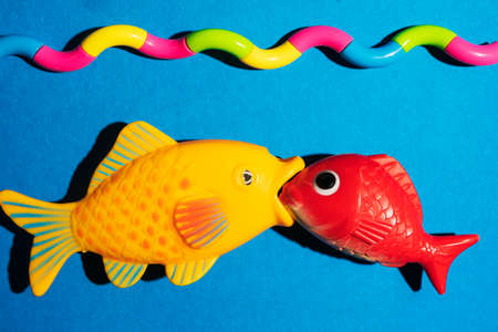 A creative composition of two fish biting each other and a stylized sea, waves, a minimalistic concept, a space for copyingの写真素材