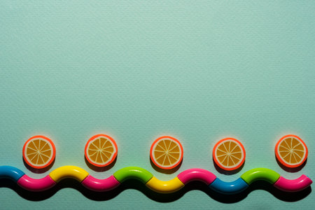 Creative composition on a turquoise background of orange slices and a wavy snake, waves, a...