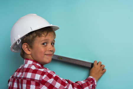 A cute boy in a plaid shirt holds a construction level in his hands, a portrait of a small builder, an engineer, a young architect.の写真素材