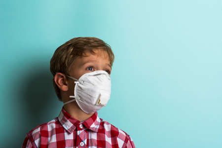a cute boy in a dust mask and a plaid shirt on a turquoise background.の写真素材