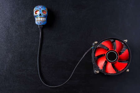 Creative composition, a computer cooler connected to a skull, an image of a computer processor cooler and a skull on top on a black backgroundの写真素材