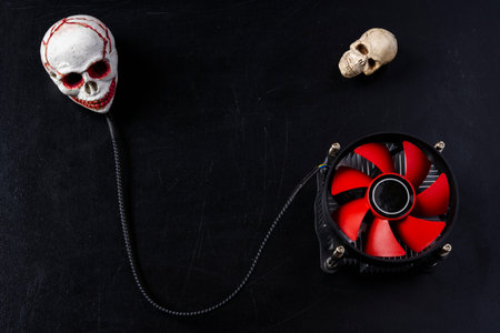 Creative composition, a computer cooler connected to a skull, an image of a computer processor cooler and a skull on top on a black backgroundの写真素材
