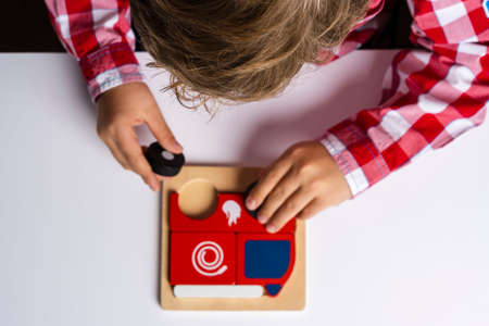 The child collects puzzles. Puzzle fire truck, the concept of early development. Children's hands put a puzzle on the table. Play classes for children.の写真素材
