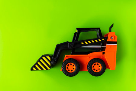 Orange Toy Loader on Green background, Mini Loader, Toy Industrial Car, Plastic Front Wheel Loader.の写真素材
