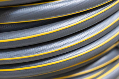 A new gray garden watering hose wound into a bay close-up.の写真素材