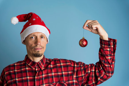 Portrait of a man in a cap of St. Nicholas and a checkered red shirt on a blue background, a guy...