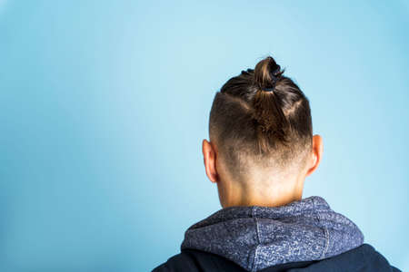 Close up side profile photo A man with a hairstyle Top Knot or A Man's Bun on a blue background, men's hairstyles, hair careの写真素材
