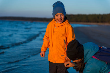 A boy and his mother walk along the bay on an autumn evening at sunset, family time outdoors.