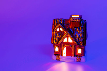 Christmas composition of a fabulous winter house with warm light in the windows, purple background, Christmas fairy-tale wooden house. Gifts. Festive composition.の写真素材
