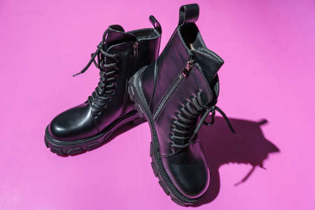 Leather Black Women's Rough Boots with Thick Soles, Laced High Fashion Boots, Rough black women's soldier boots on a pink backgroundの写真素材