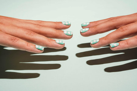 Two beautiful female hands with colored manicure in turquoise tones are reaching out to each otherの写真素材