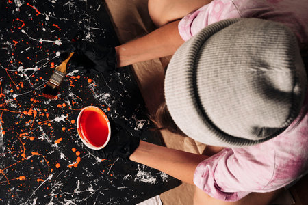 A girl designer artist draws a background for photos on a large wooden sheet using a brush and paintsの写真素材