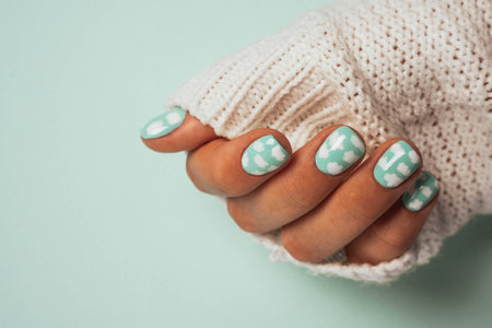 Beautiful thin female fingers with a colored manicure in the sleeve of a white warm wool sweater