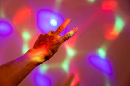 The mans hand shows the sign of freedom, victoria, against the background of running colored highlightsの写真素材