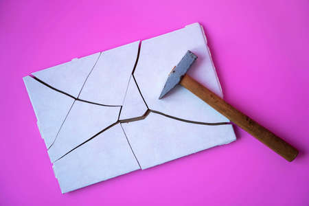 Tile broken into pieces with a hammer on a pink backgroundの写真素材