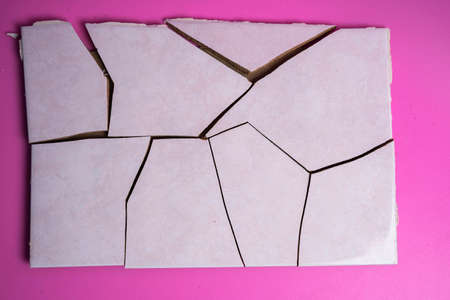 Cracked ceramic tile, broken into pieces on a pink background, tile fragmentsの写真素材