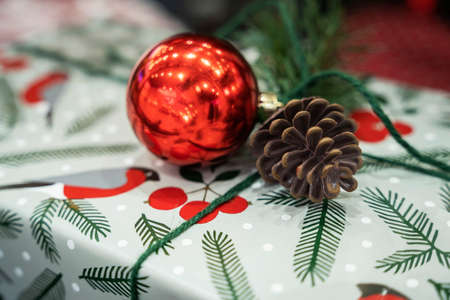 A Christmas gift in a box and a Christmas ball, a cone and branches of a fir treeの写真素材
