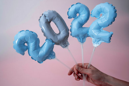 a womans hand holds inflatable figures with numbers 2022