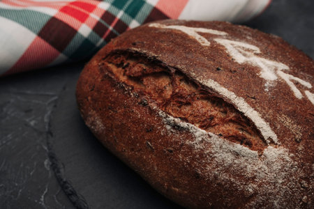 Freshly baked warm delicious rye round bread close-up and a kitchen checkered towel. The concept of...