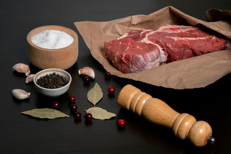 A piece of fresh Raw meat wrapped in kraft paper, garlic cloves, Bay leaf