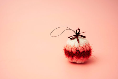 knitted, soft, colored handmade Christmas ball on a light peach background