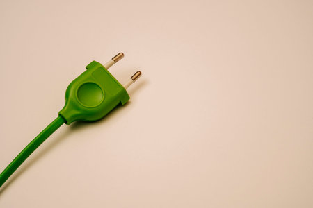 green electric wire and plug on a light peach background