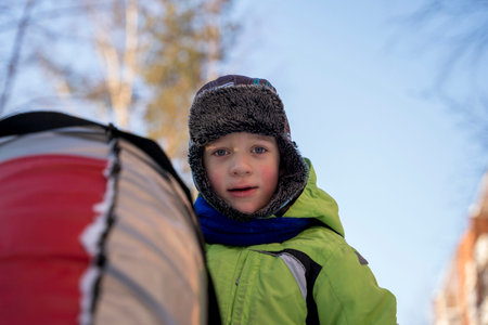 Funny Caucasian boy 5 years old rides in winter on a big inflatable cheesecakeの写真素材