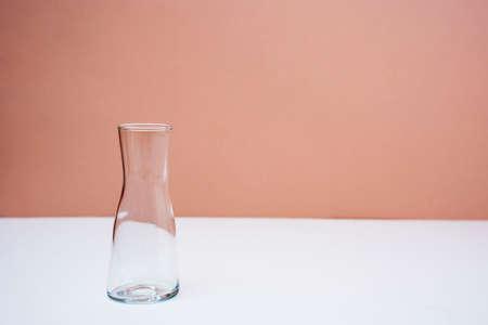 An empty glass vase on the table on a peach backgroundの写真素材