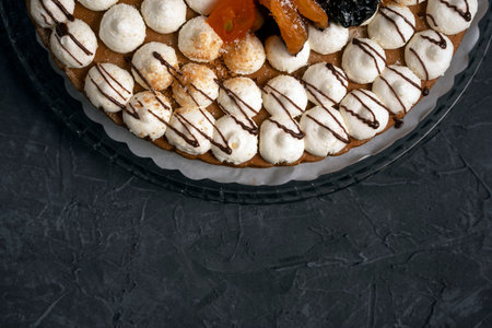 Delicious fresh beautiful round cream cake decorated with prunes, dried apricots and chocolate