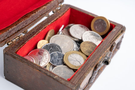 a small old wooden chest with coins on a white background. savings