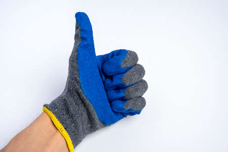 a mans hand in blue rubberized work gloves shows a thumbs up on a blue backgroundの写真素材