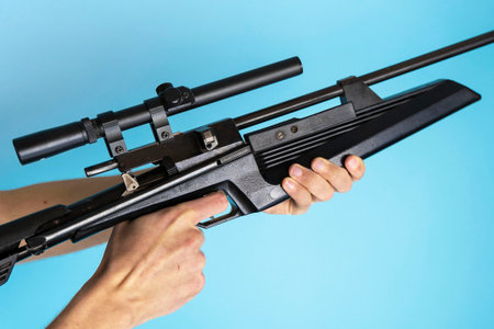 rifle with optical sight in mens hands on a blue background, weaponsの写真素材