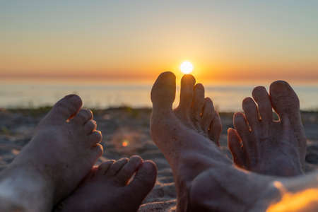 feet of the father and child in the sand on the beachの写真素材