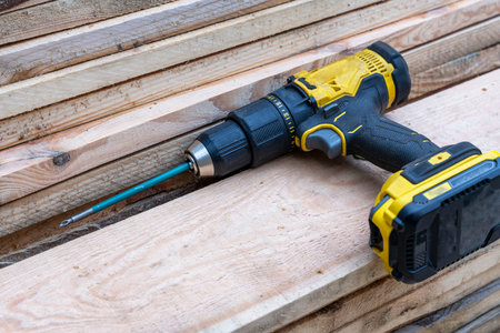 cordless screwdriver lying on a stack of wooden boards. Construction
