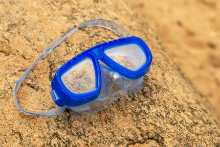 Childrens swimming mask lying on a stone on the shore of the lake
