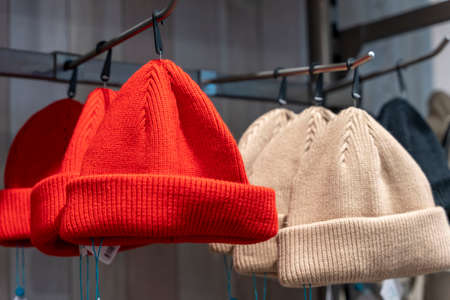 red and beige fashionable knitted hats on the shelf in the storeの写真素材